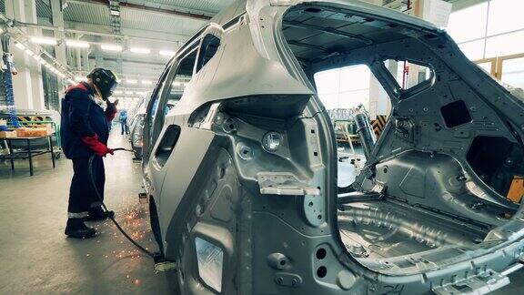 汽车厂工人正在焊接一辆未完工的汽车车身