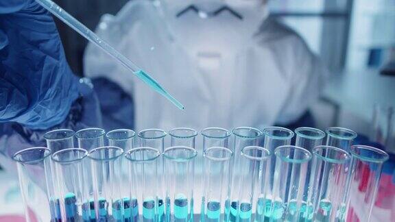 实验室研究人员用吸管将蓝色液体倒入试管中