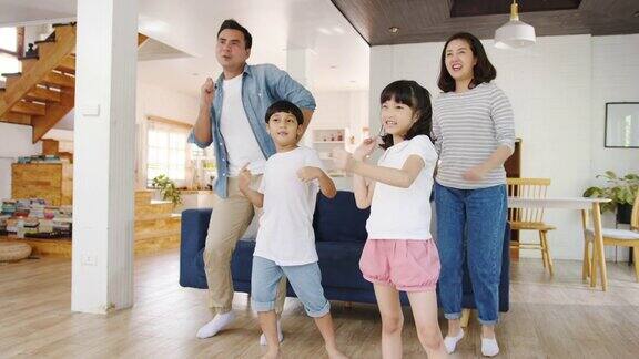 慢动作-快乐快乐的亚洲家庭在现代家庭的客厅里听音乐和跳舞