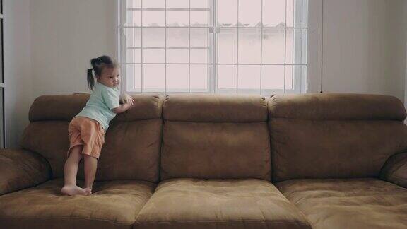 一个亚洲小女孩喜欢在客厅的沙发上跑跳