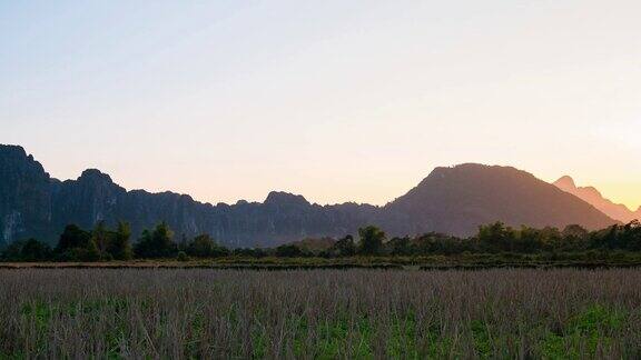 时光流逝:万荣背包客旅游目的地老挝亚洲夕阳下风景秀丽的悬崖峭壁和岩石尖峰稻田谷地令人叹为观止的景观