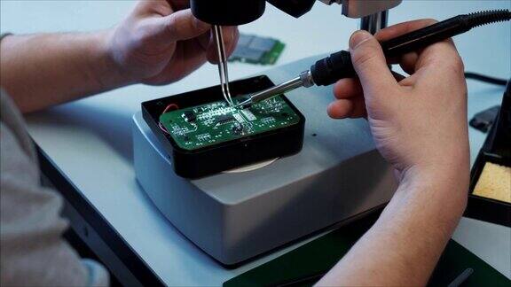 专业技术人员用烙铁修理显微镜台上的无人机组件