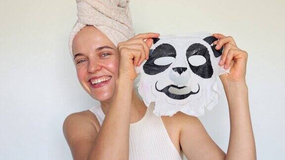 补水面膜胶原蛋白有益于皮肤健康皮肤嫩肤程序抗衰老护肤品戴着熊猫嘴型口罩洗完澡后快乐的女孩用毛巾敷在头上
