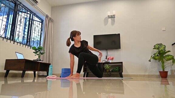 有吸引力的年轻亚洲女人锻炼和做瑜伽的位置而休息在家里