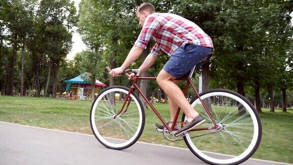 在公园路上骑车的运动男年轻英俊的男人在户外骑着一辆老式自行车健康积极的生活方式侧视图关闭慢动作低角度视图