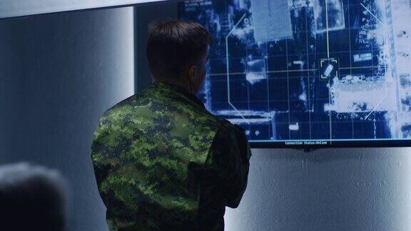 军人军官在墙上电视屏幕上观看目标的卫星监控录像汽车跟踪在监控中心系统控制室的秘密军事间谍行动