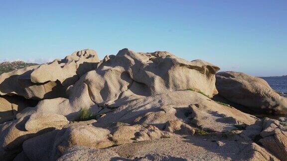 日落时分撒丁岛平静的海滩上有巨大的岩石