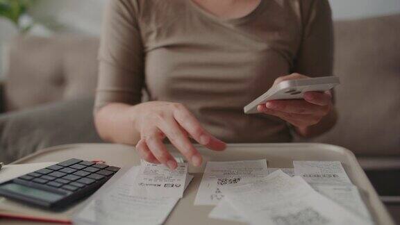 一名妇女在手机上计算她的预算和支出的收据女性的手在计算每月的支出