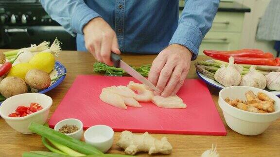 男人的手在切菜板上切鸡柳的特写