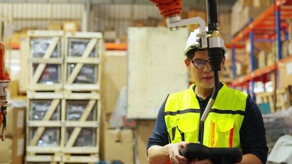 4K亚洲男工程师在工厂用机械臂工作