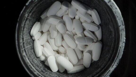 一个黑色的罐子上面有白色的药片在黑色的背景上旋转特写镜头前视图