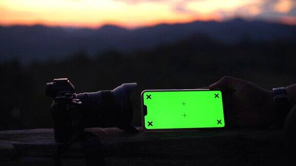 特写的男人拿着智能手机的绿色屏幕与自然戏剧性的天空作为背景色度键