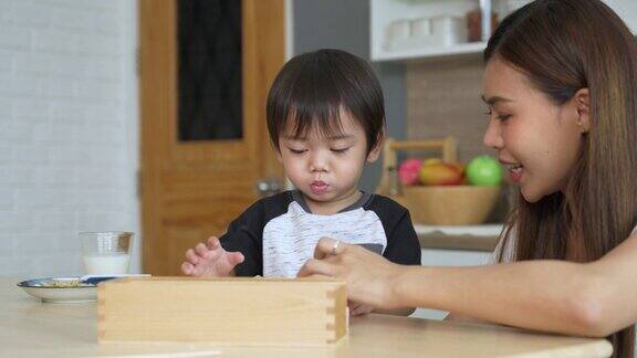 小男孩吃着食物和他的妈妈玩玩具