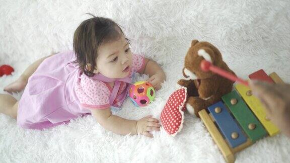可爱的小女孩在地板上爬行看着玩具