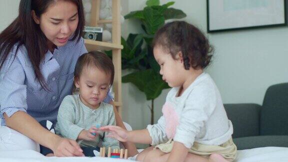 亚洲母亲和婴儿的孩子女孩学习玩彩色的木制玩具在床上