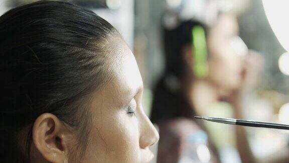 化妆师在美女脸上涂上眼影粉