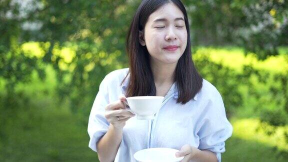 女人享受早晨的咖啡快乐早上在家里喝一杯咖啡在阳光下呼吸新鲜空气