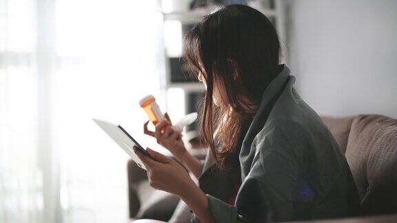 生病的亚洲妇女有视频电话与她的医生在数字平板电脑在家里