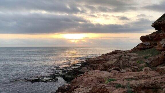 日出时的小海湾和风景如画的海滩地中海岩石海岸的红色斜坡波浪拍打着岩石海岸版本2