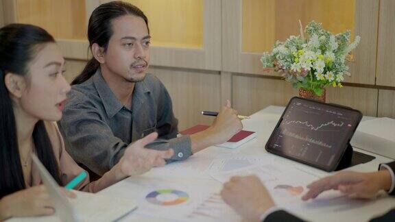 一群亚洲商人在会议上分析营销计划投资和数据图表文件高级财务分析师在分析中使用平板电脑向新同事讲解股市走势