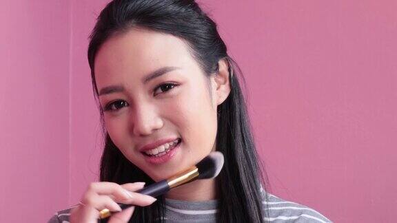 女人化妆一位年轻的亚洲女子用化妆刷在脸上刷腮红化妆品