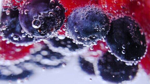 慢镜头和超级微距拍摄清凉苏打水汽水蓝莓和树莓在玻璃微距特写气泡