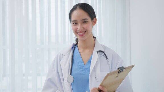 美丽的医生画像站在办公室医院迷人的年轻治疗师、女执业药剂师微笑着看着镜头成功地从医院的治疗工作