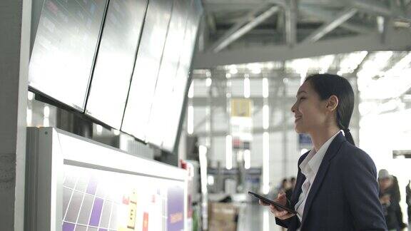 女商人拿着智能手机看机场登机牌