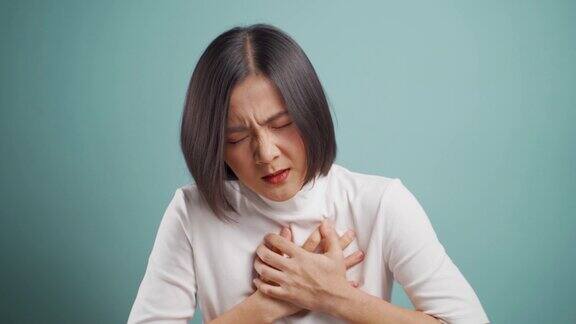 一名亚洲女性胸痛孤立地站在蓝色背景下4k的视频卫生保健