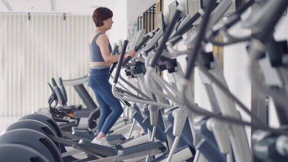 妇女在椭圆机跑步新常态和现代健身房