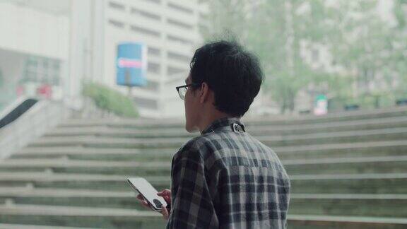 一名男子使用智能手机从现代办公大楼走出来