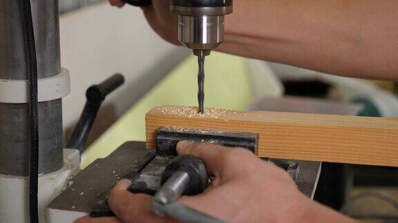 一个男木匠用钻头在木条上钻孔的特写