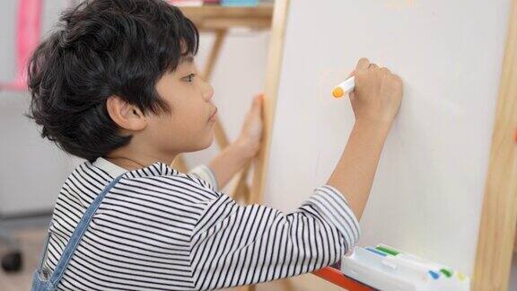 亚洲小男孩在白板上做磁性磁性白板在教室里进行教育多民族幼儿教师和学生课堂儿童教育与学习理念