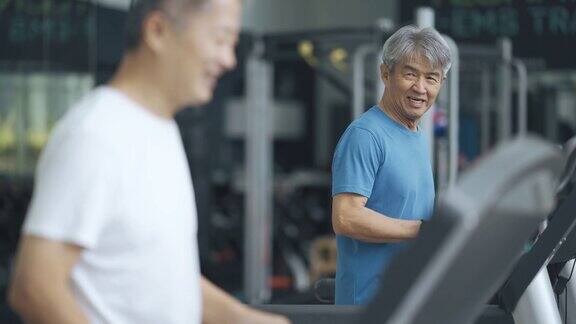两名中国老人一起在健身房的跑步机上跑步