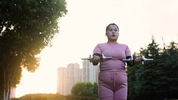 亚洲身材高大的女性在户外用哑铃锻炼