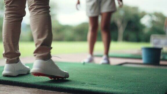 低角度亚洲华人女子在练习前与教练在高尔夫练习场进行伸展热身运动