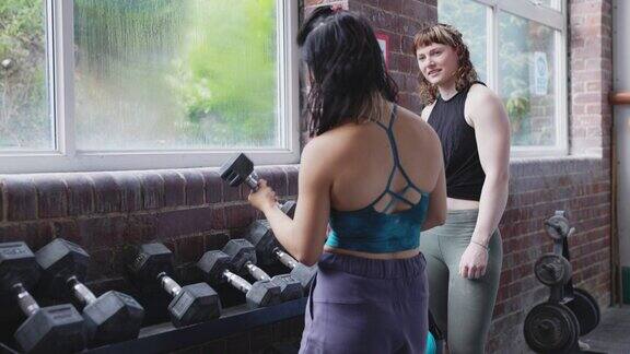 女人们在健身房用哑铃聊天和锻炼