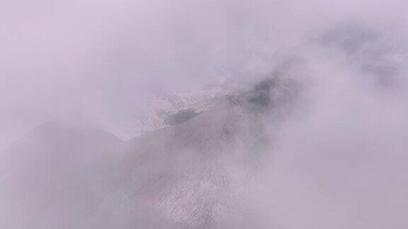 一个晴朗的下午在山区鸟瞰穿过空中蓬松的云层在山和云上的真实飞行