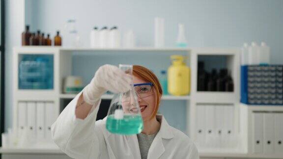 年轻的红发女子穿着科学家制服在实验室里拿着试管