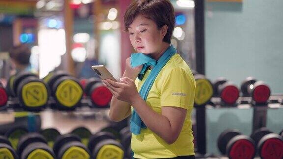 一名女子在健身房锻炼后使用智能手机