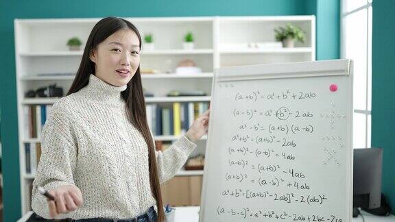 在图书馆大学年轻的中国女学生微笑着自信地解释数学练习