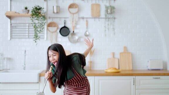 亚洲年轻女子在厨房跳舞女性在周末的空闲时间快乐和放松