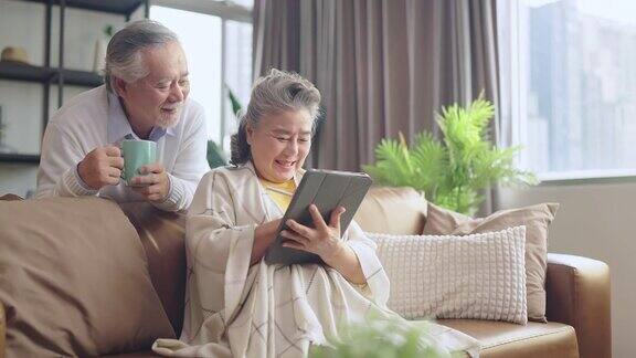 亚洲老年退休夫妇在沙发上与家人一起享受视频通话幸福地笑着笑着快乐地呆在家里亚洲老年成熟成人居家隔离期概念