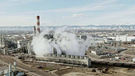 在一个阳光明媚的日子里从科罗拉多州丹佛市中心附近的发电厂升起的蒸汽以落基山脉为背景