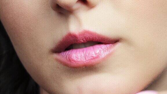 一个女人涂着粉色唇膏的嘴唇的特写镜头