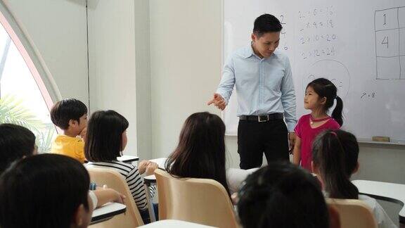 一位亚洲老师在学校介绍班上的新学生小男孩和小女孩一起交了新朋友理念教育礼仪之邦