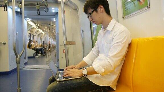 年轻人在火车上使用手提电脑