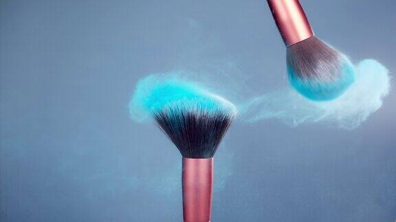 化妆刷与蓝色粉末爆炸在蓝色背景超级慢动作