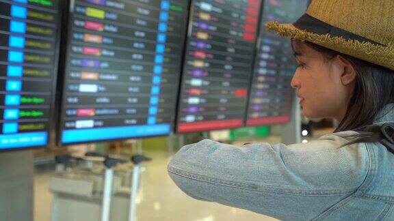 女旅客在机场候机楼查航班时刻表