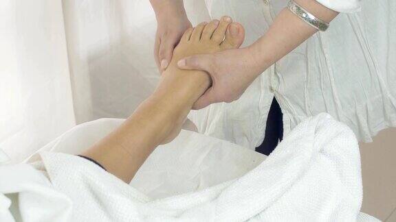 在沙龙里女按摩师为女士做左脚按摩治疗过程